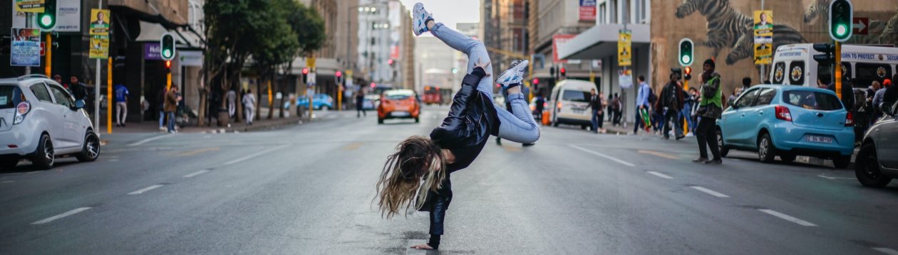 A woman does a handstand on a street.