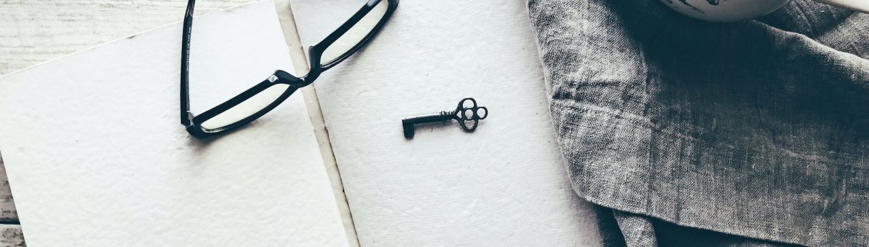 A key and a pair of glasses on a table.