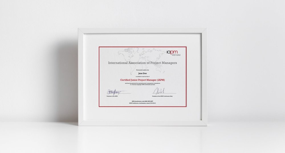 The Certified Junior Project Manager certificate is in a white picture frame on a white surface.