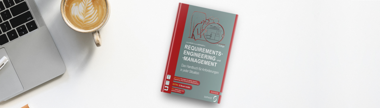 Chris Rupp's book "Requirements-Engineering und -Management" lies on a table next to a laptop and a cappuccino 
