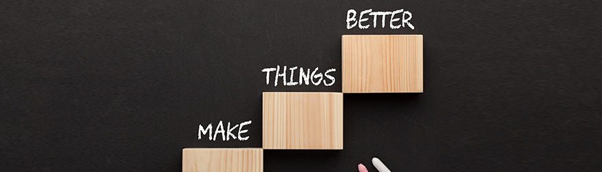 Schriftzug "make things better" über Holzblöcke auf eine Tafel geschrieben.