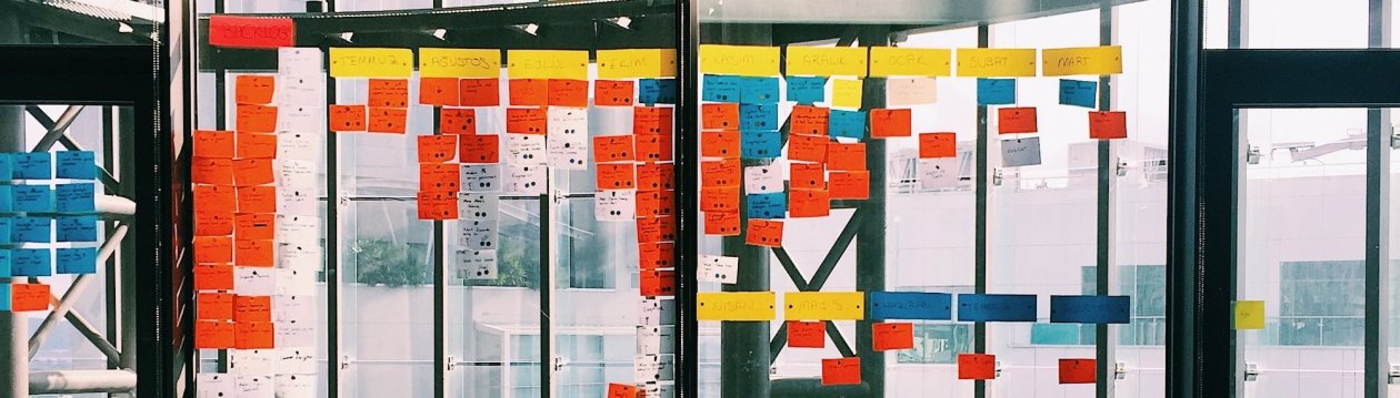 Colourful Post-its on the glass wall, partly labelled, in the office.