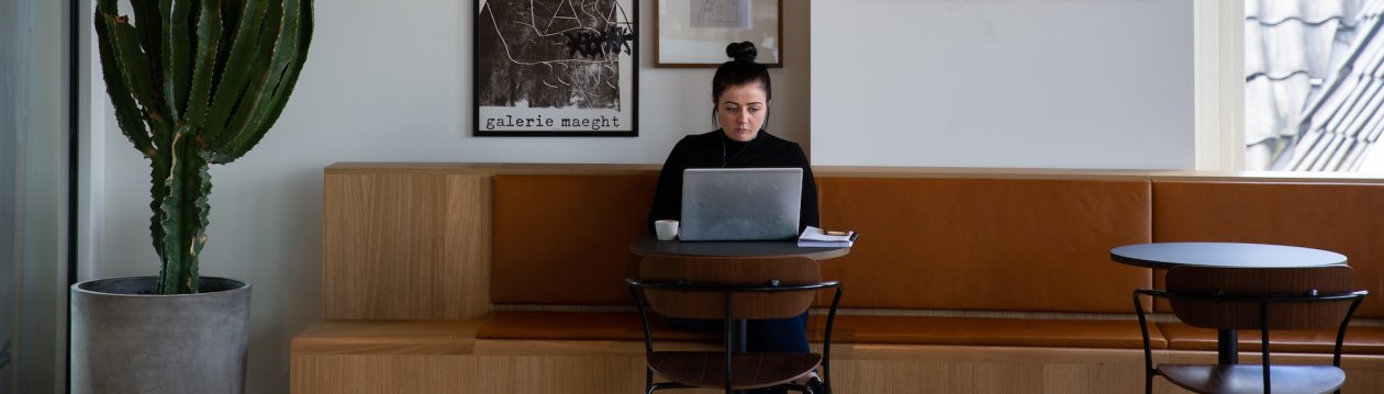 Eine Person sitzt in einem Cafe an ihrem Laptop.