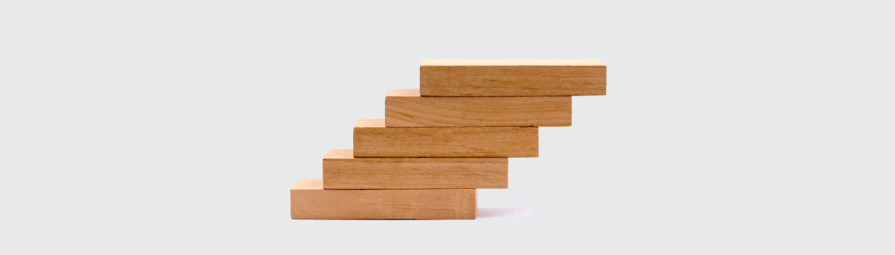 Five wooden blocks are stacked to form a staircase.