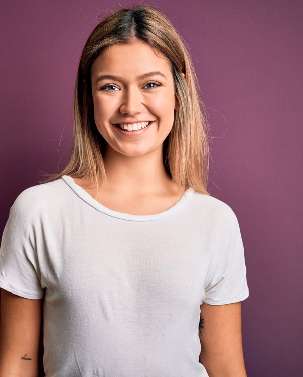 Young woman smiling at camera. The background is purple.