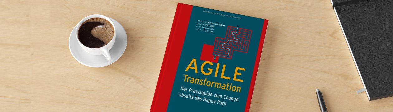 Auf einem Tisch liegt das Buch "Agile Transformation", daneben sind eine Tasse Kaffee, ein Stift und ein Notizbuch zu sehen Auf einem Tisch liegt das Buch "Agile Transformation", daneben sind eine Tasse Kaffee, ein Stift und ein Notizbuch zu sehen