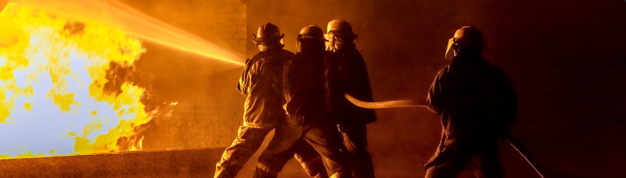 4 Feuerwehrmänner, die einen starken Brand löschen