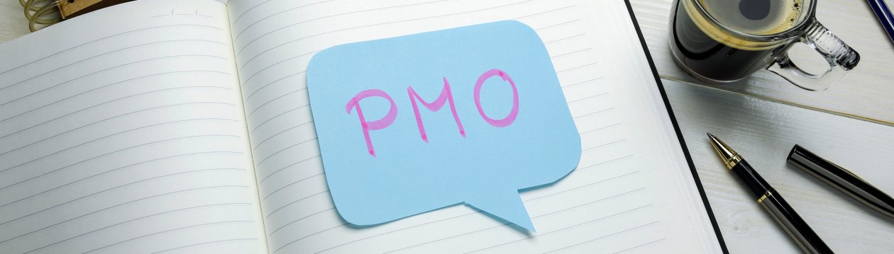 In einem Notizblock liegt ein blaues Post-it in Form einer Sprechblase mit der Aufschrift "PMO"