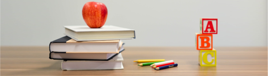 Stacked books, an apple, pens and wooden blocks labelled A, B and C. [1]