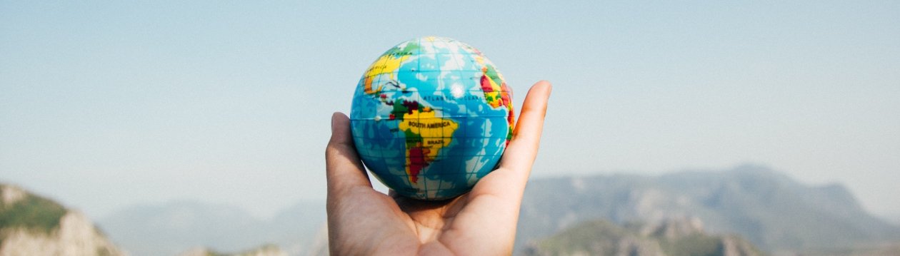 A person holds a globe in their hand.