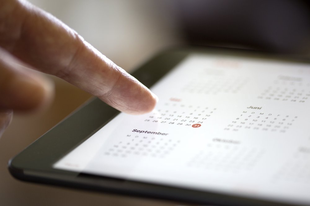 Eine Person tippt auf einen Kalender auf einem Tablet.