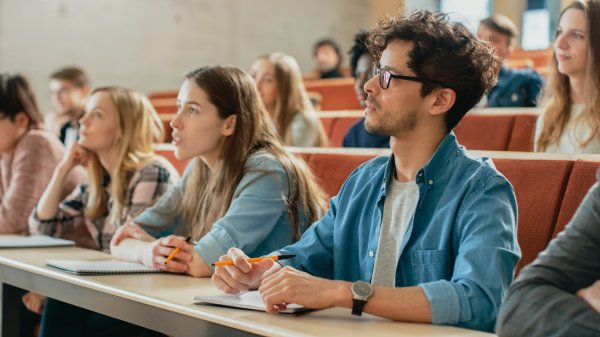 Several people are sitting in a lecture hall.