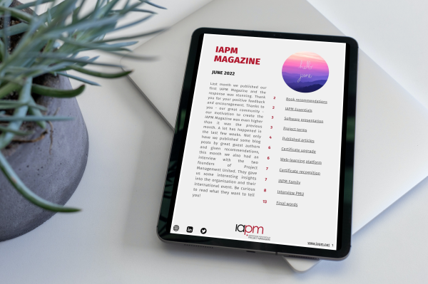 Tablet liegt neben einer Pflanze auf einem Tisch und zeigt das Cover des IAPM Magazine June.