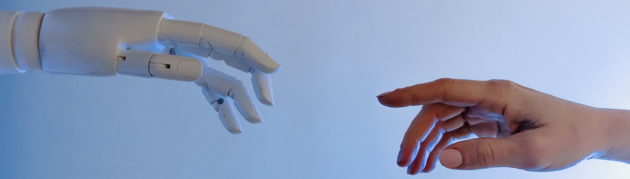 Eine weiße Roboterhand und der Finger eines Menschen. Eine weiße Roboterhand und der Finger eines Menschen.