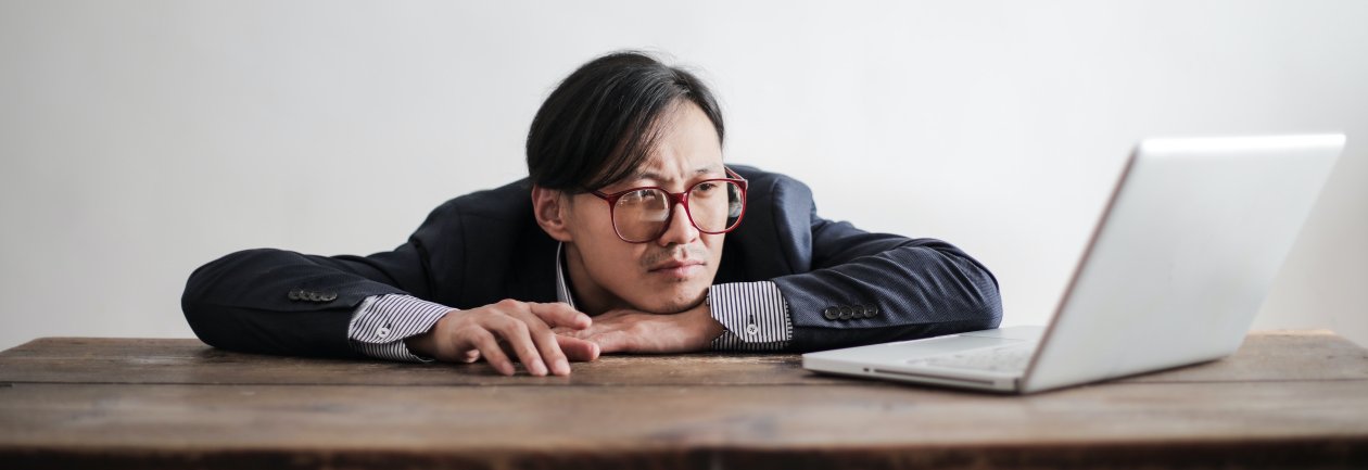 Man rests his face on one hand and looks at a laptop, waiting. Man rests his face on one hand and looks at a laptop, waiting.