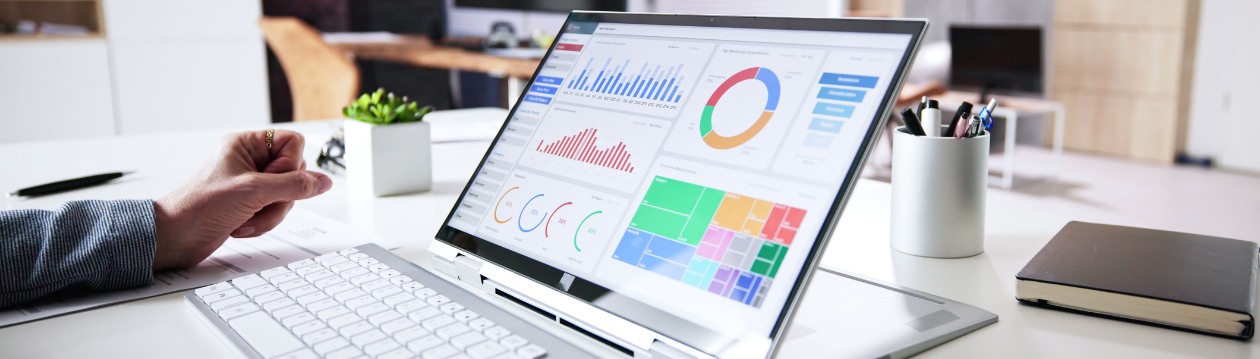Ein Laptop auf einem Schreibtisch zeigt mehrere bunte Diagramme und Grafiken auf einem Dashboard.