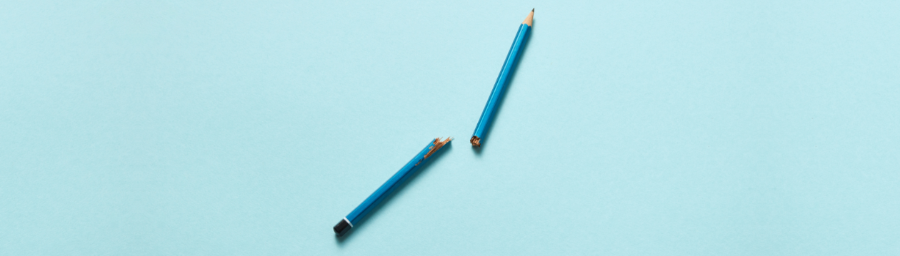 Zwei Teile eines zerbrochenen blauen Bleistifts liegen auf hellblauem Hintergrund. Zwei Teile eines zerbrochenen blauen Bleistifts liegen auf hellblauem Hintergrund.