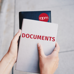 One person holds a book with the words 'DOCUMENTS' and one with the IAPM logo.