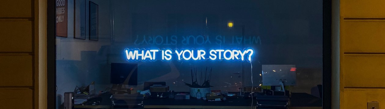 A neon sign "WHAT IS YOUR STORY?" 