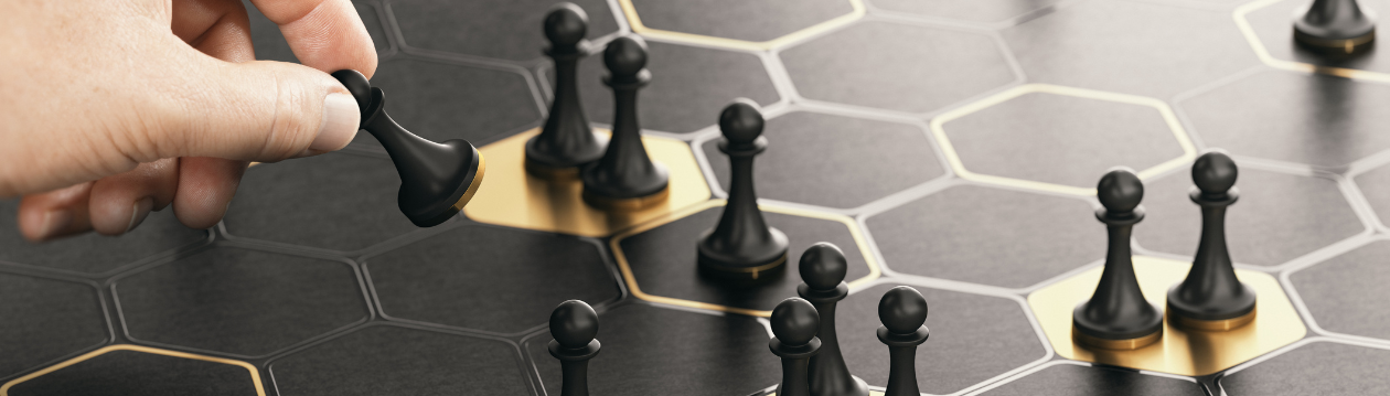 Hand bewegt eine schwarze Schachfigur auf einem hexagonalen Spielfeld mit mehreren schwarzen Bauern.