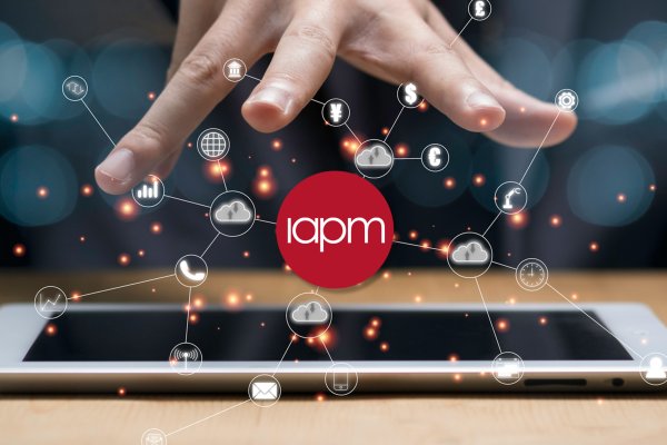 A person holds their open hand over the IAPM logo and digital symbols. A person holds their open hand over the IAPM logo and digital symbols.