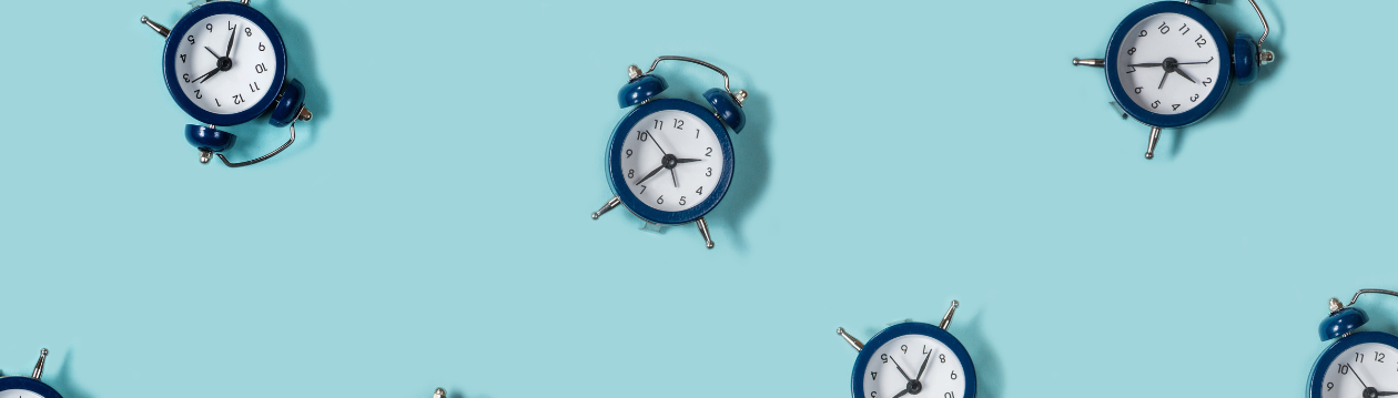 Several blue alarm clocks are scattered on a light blue background, partially cropped and shown from different angles.