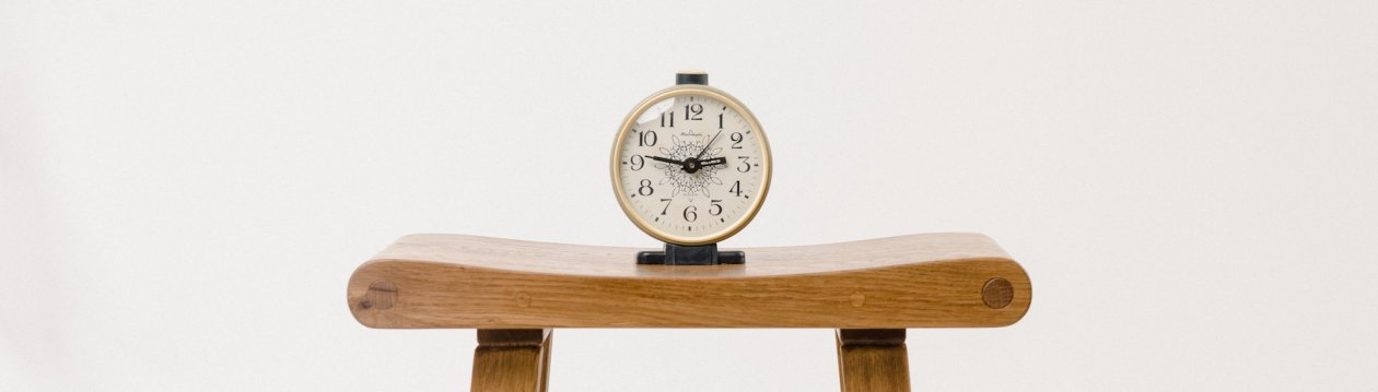 A clock on a wooden chair.