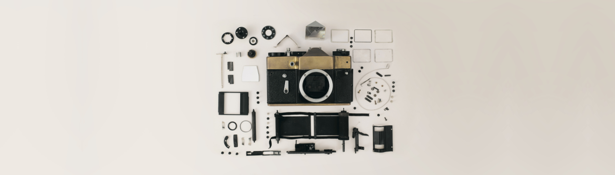 A black and gold camera in individual parts on a white background.