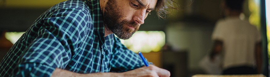 Man with blue shirt is writing something.